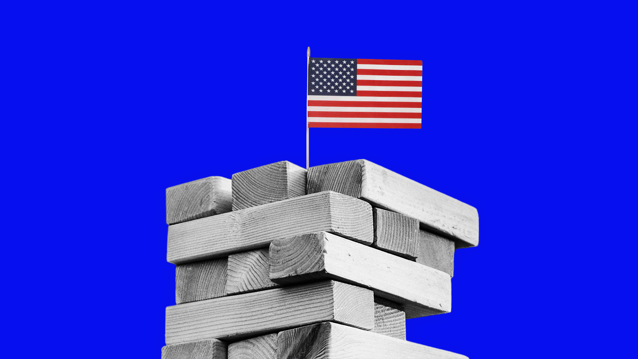 A Jenga-type tower of wooden building blocks with a U.S. flag planted at the top