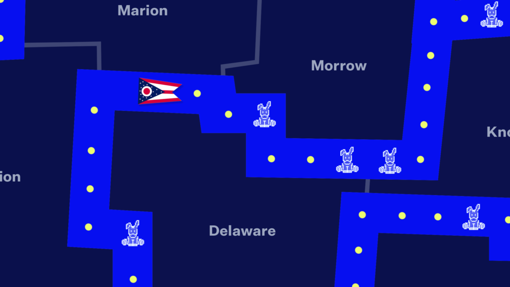 A dark-blue map of Ohio counties with a Pac-Man game superimposed on top, with Pac-Man replaced by the Ohio flag and the ghosts replaced by donkeys.