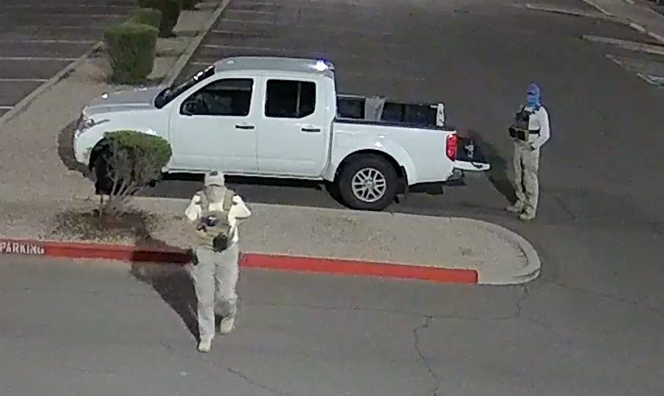 Two armed individuals dressed in tactical gear at a Mesa ballot drop box.