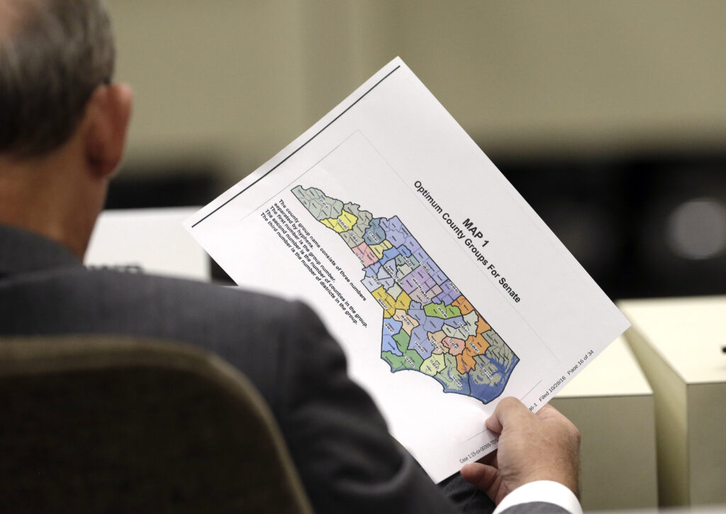 In this Wednesday, July 26, 2017 photo, a lawmaker holds a districting map during a joint select committee meeting on redistricting in Raleigh, N.C. North Carolina judges on Monday, Oct. 28, 2019 blocked the state's congressional map from being used in the 2020 elections, ruling that voters had a strong likelihood of winning a lawsuit that argued Republicans unlawfully manipulated district lines for partisan gain. (AP Photo/Gerry Broome)