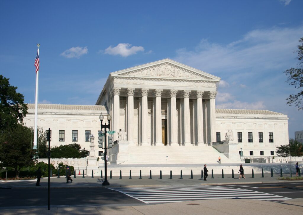 Photograph of U.S. Supreme Court in Washington D.C. The photograph features the U.S. Supreme Court in the center with the blue sky above the Court. (Adobe Stock)