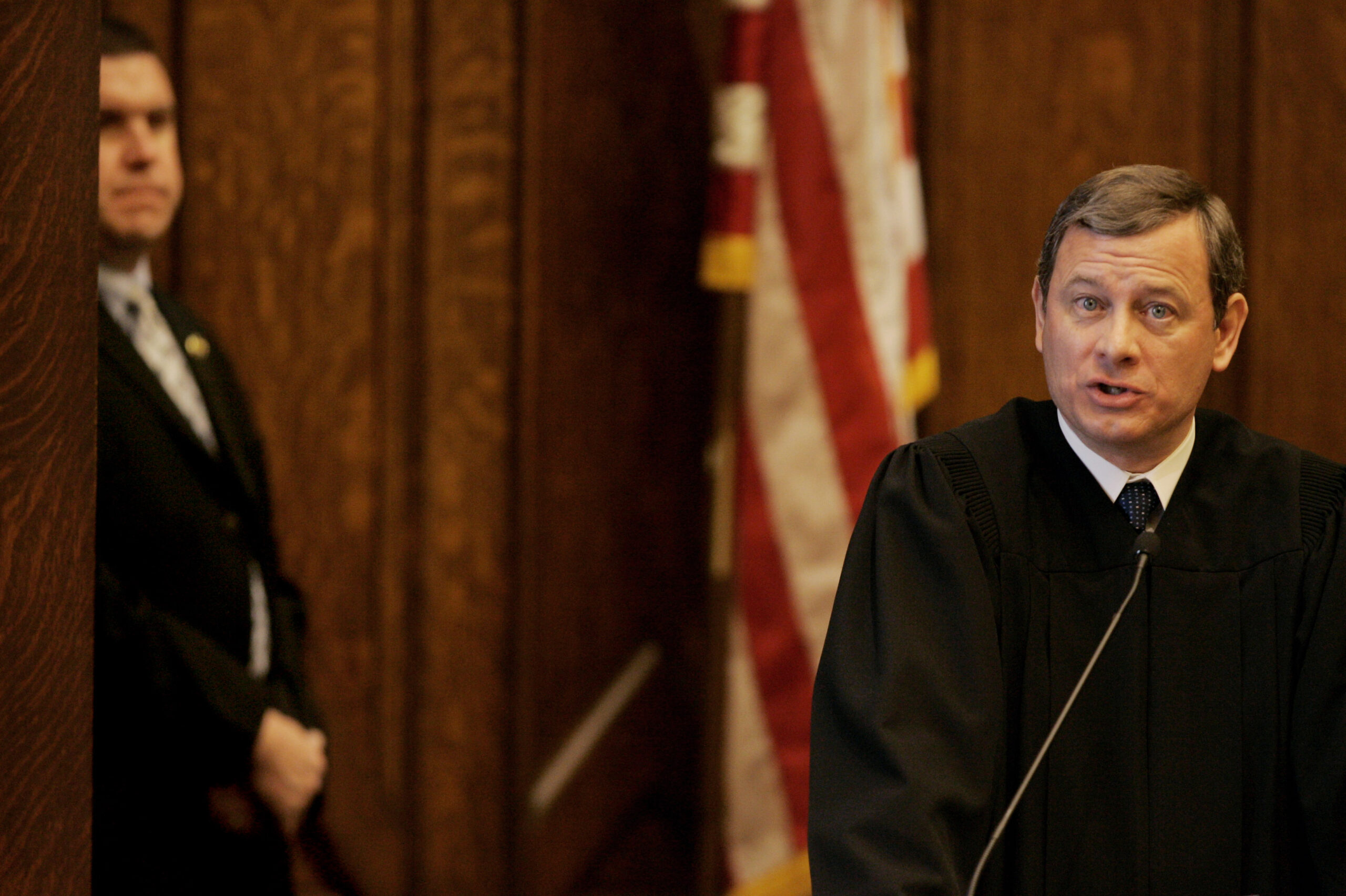 U.S. Supreme Court Chief Justice John G. Roberts, Jr., makes remarks at the opening celebration of the Centennial of the U.S. Courthouse in Providence, RI., as a member of his security team looks on Tuesday morning, Feb. 12, 2008. (AP Photo/Stephan Savoia)