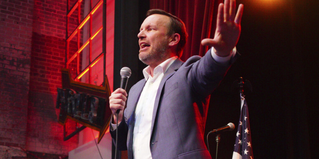 Sen. Chris Murphy speaking on stage holding a microphone.
