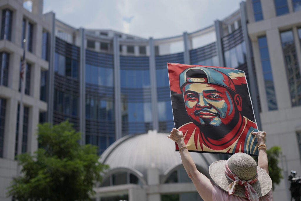 A person holding a sign with Kilmar Abrego Garcia's face on it.