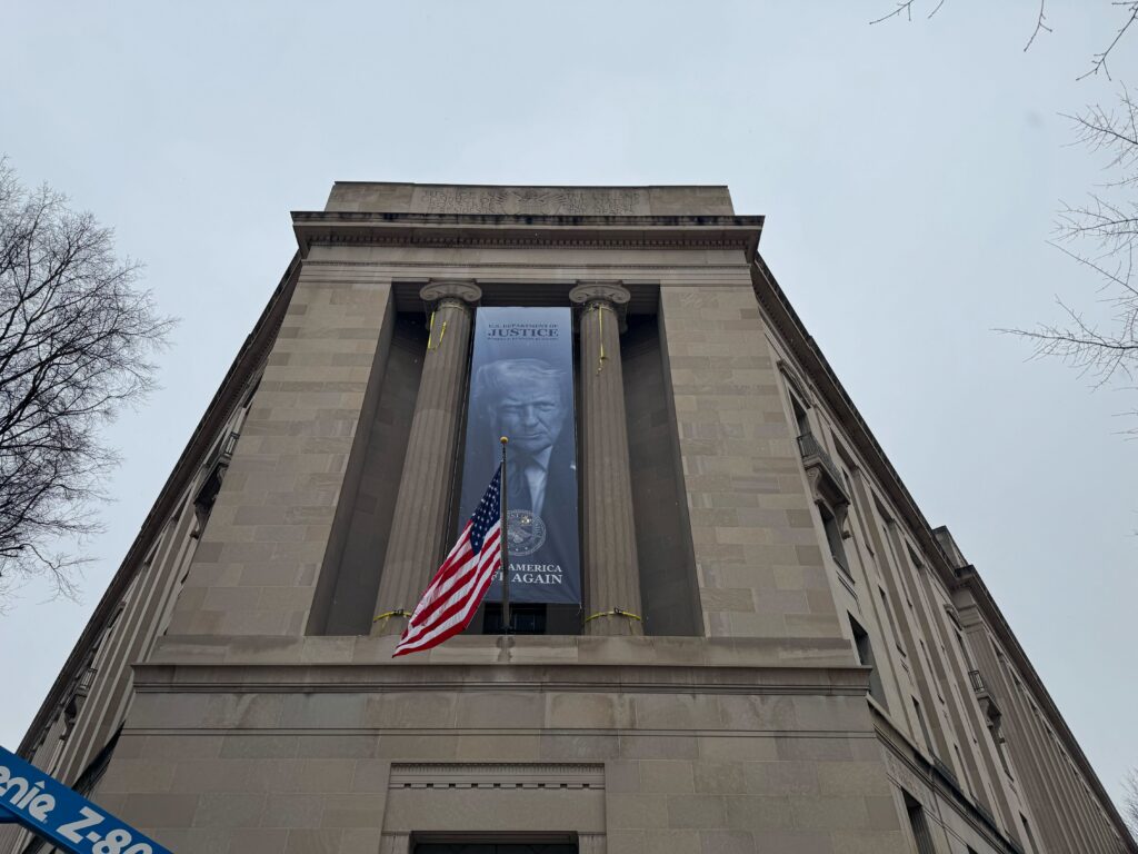 A banner with President Donald Trump's visage and 'Make America Great Again' campaign slogan is draped from the Department of Justice's main building in Washington, D.C. on Feb. 19, 2026 (Photo by Jacob Knutson/Democracy Docket)