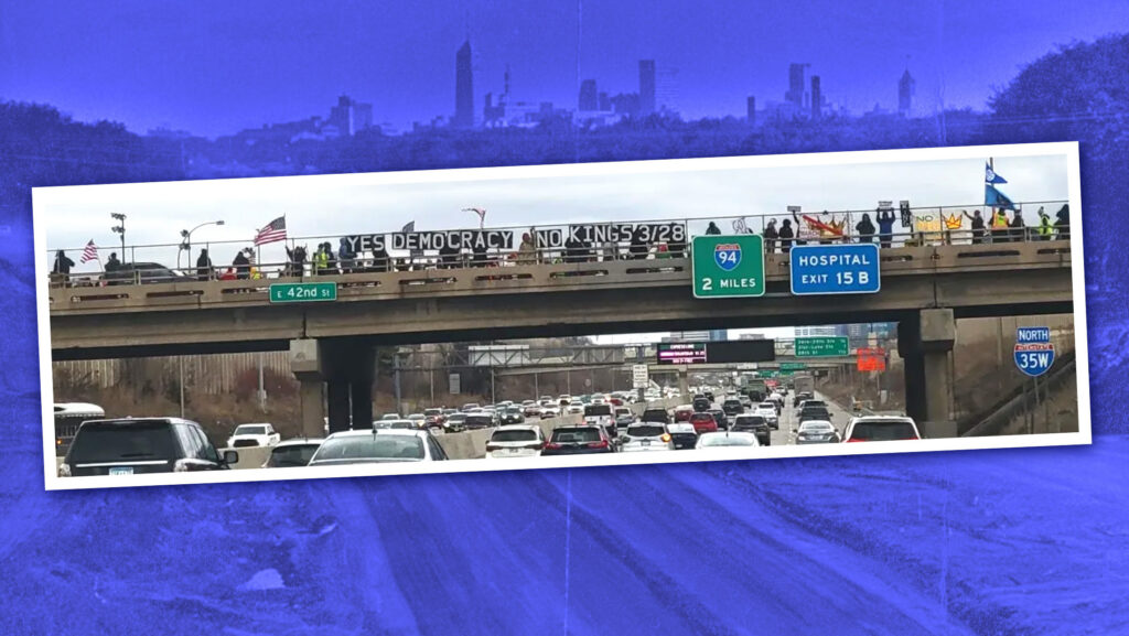 Community members hold a sign that reads "YES DEMOCRACY NO KINGS 3/28" above a high traffic Interstate 35 highway in Minnesota.