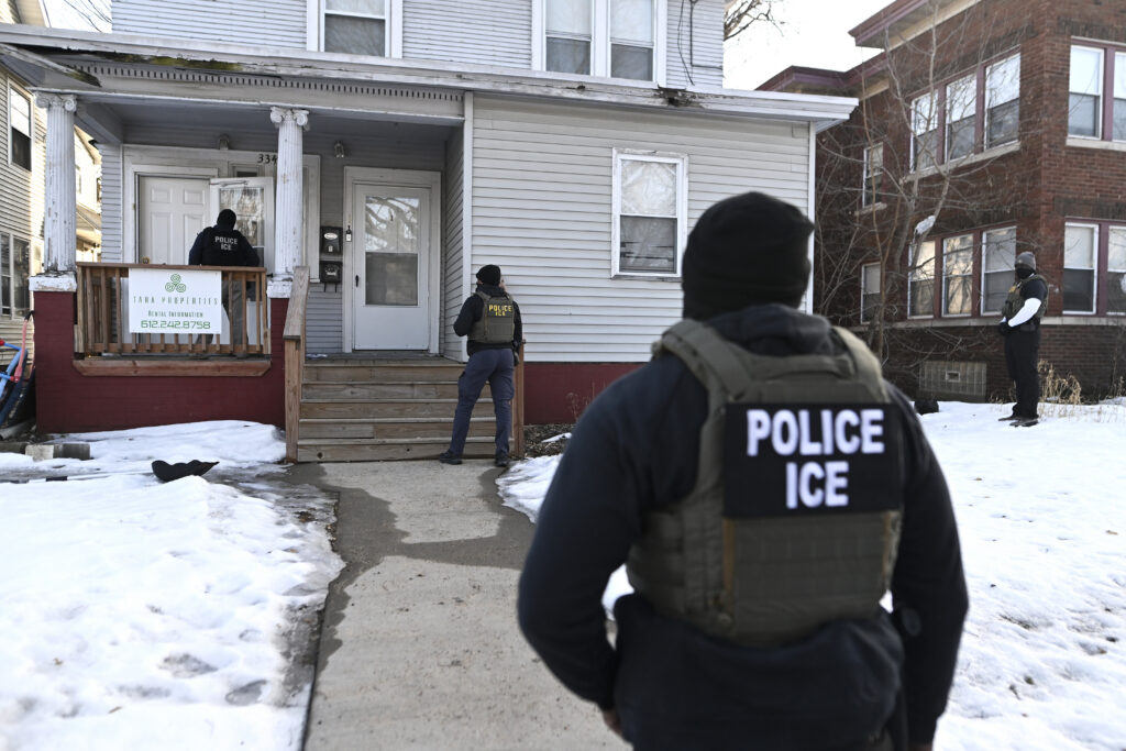 Immigration and Customs Enforcement agents approach a house before detaining two people in January 2026 in Minneapolis, Minnesota.