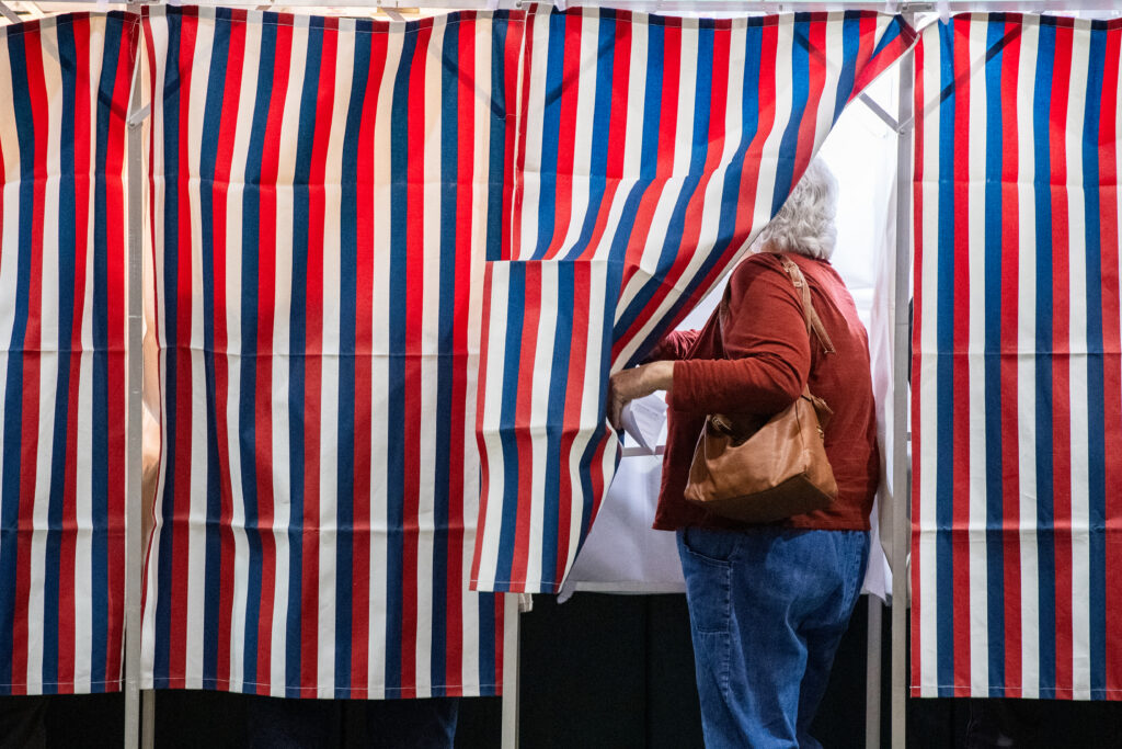 A person entering a voting booth at an elementary school in Colebrook, New Hampshire, on Election Day in 2024. (Photo by Joseph Prezioso/AFP via Getty Images)
