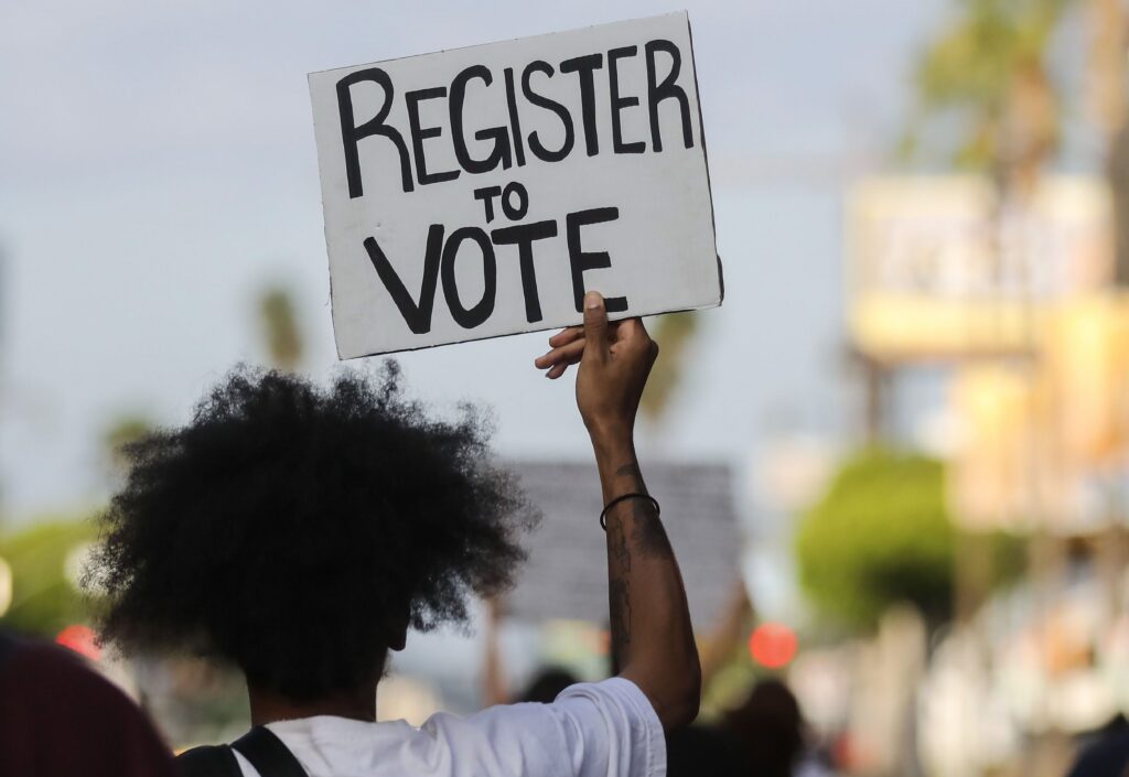 A protester carries a "Register to Vote" sign during a demonstration in June 2020 in Los Angeles. (Photo: Mario Tama/Getty Images)