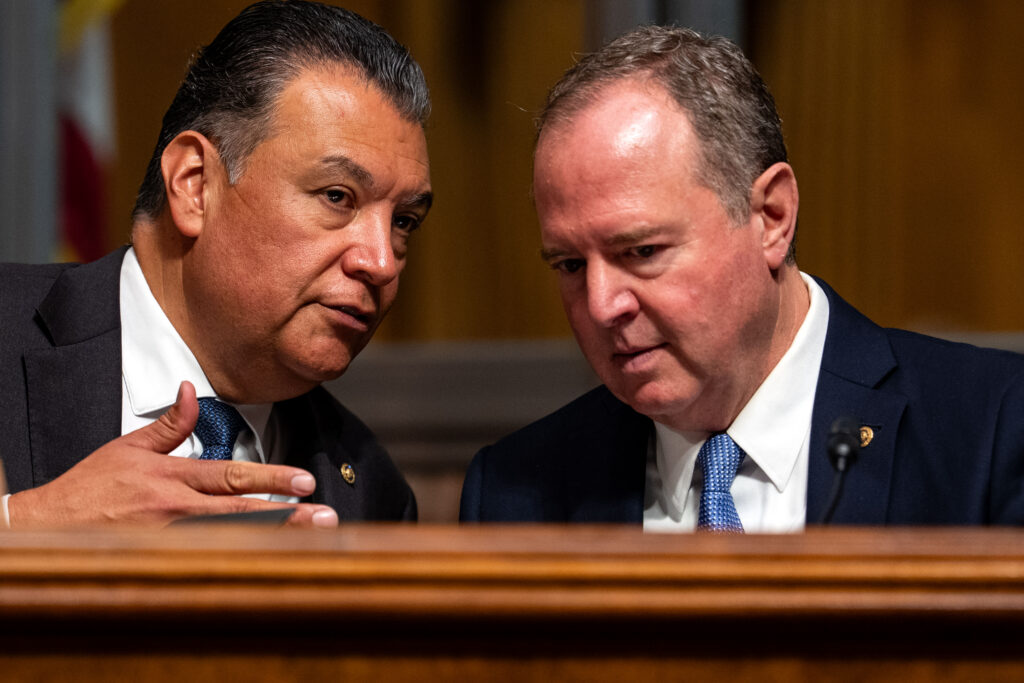 Sen. Alex Padilla (D-Calif.) and Sen. Adam Schiff (D-Calif.) speaking with each other during a Senate subcommittee hearing in September 2025 in Washington, D.C. (Photo: Kent Nishimura/Getty Images)
