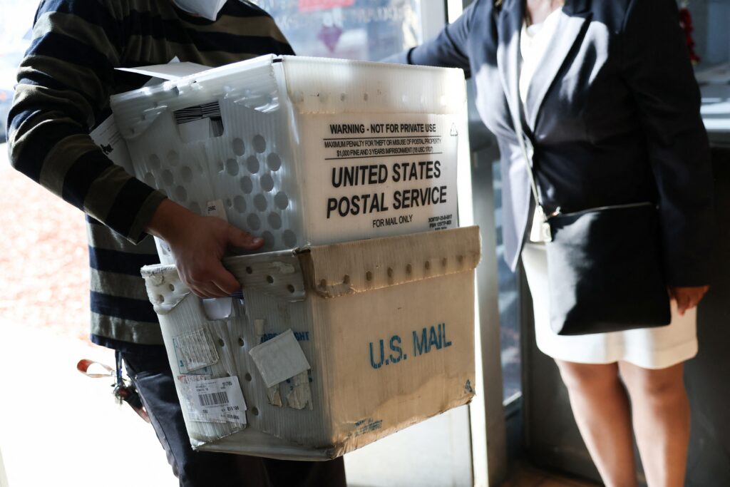 A person carrying packages into a USPS post office in Gardena, California in December 2025. (Photo: Patrick T. Fallon/AFP via Getty Images)