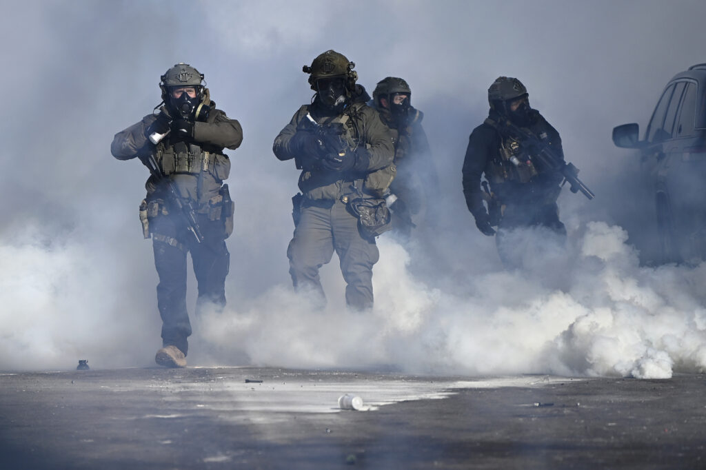 Federal agents point weapons amid tear gas fired at protestors on January 24, 2026 in Minneapolis, Minnesota.