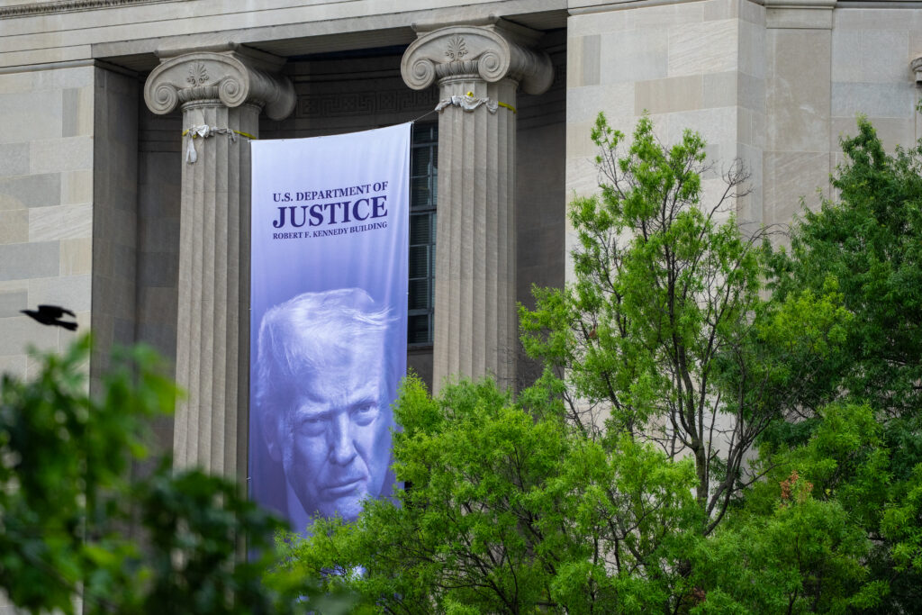 A banner featuring President Donald Trump hanging on Justice Department headquarters in Washington, D.C. in June 2026. (Photo: Ken Cedeno/AFP via Getty Images)