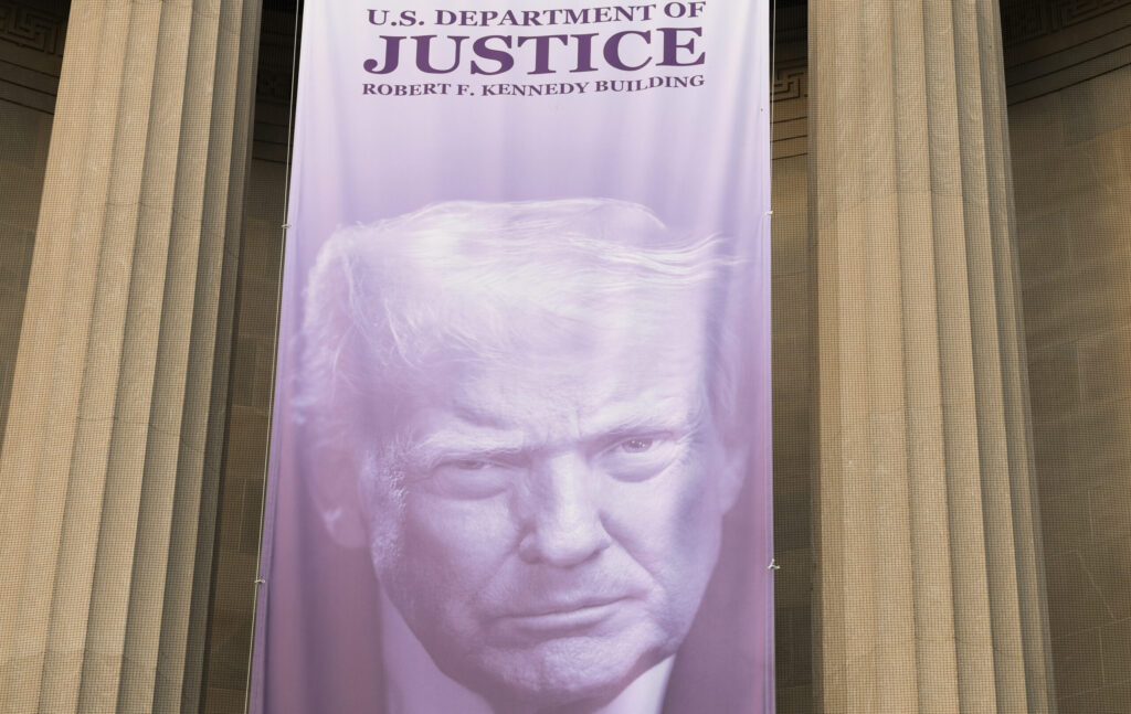 A large blue banner featuring President Trump's face is seen on the U.S. Department of Justice Building in August 2026 in Washington, D.C. (Photo: Anna Moneymaker/Getty Images)