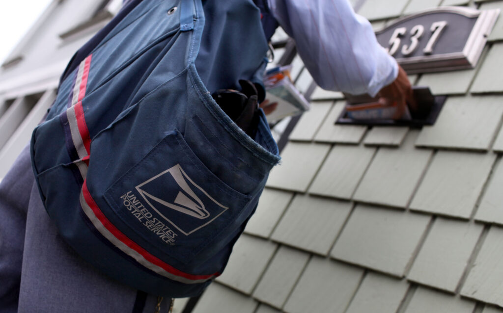 A U.S. Postal Service letter carrier placing mail in a mailbox in San Francisco in 2009. (Photo: Justin Sullivan/Getty Images)